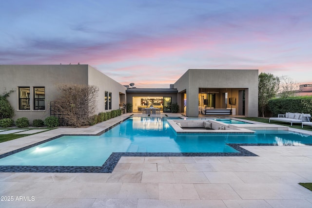 pool at dusk featuring a jacuzzi, a patio area, an outdoor pool, and an outdoor hangout area