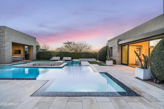 pool at dusk featuring an in ground hot tub, a fenced in pool, and a patio