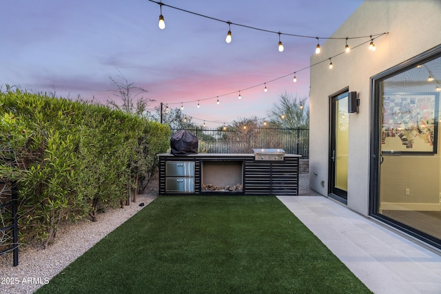 yard at dusk with an outdoor kitchen and fence