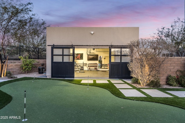 rear view of house with stucco siding and fence