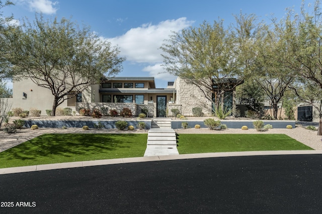 view of front facade with a front lawn, stone siding, and stucco siding