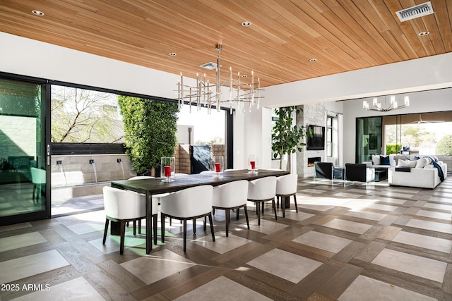 dining area featuring visible vents, a lit fireplace, an inviting chandelier, and wooden ceiling