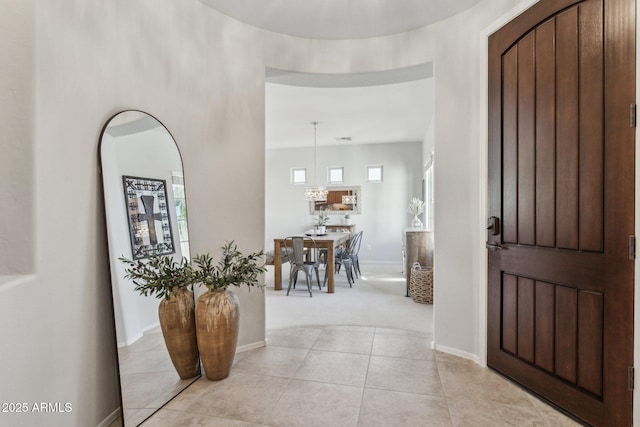 foyer entrance with light tile patterned flooring, baseboards, and light carpet