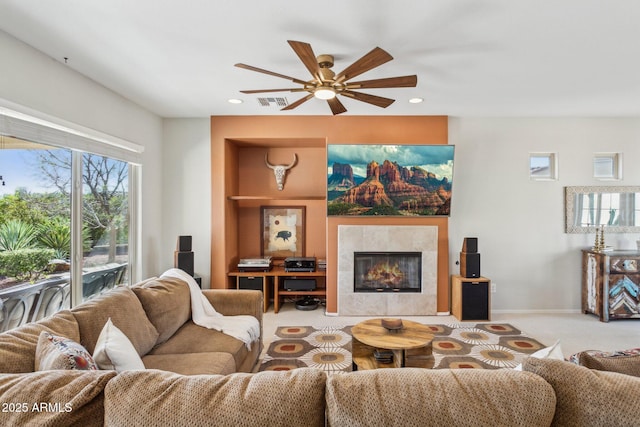 living area featuring visible vents, baseboards, carpet floors, a fireplace, and a ceiling fan