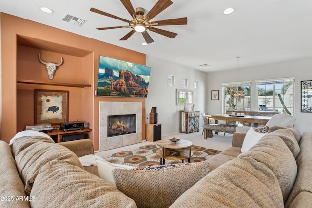 living room with visible vents, carpet, recessed lighting, ceiling fan with notable chandelier, and a tile fireplace