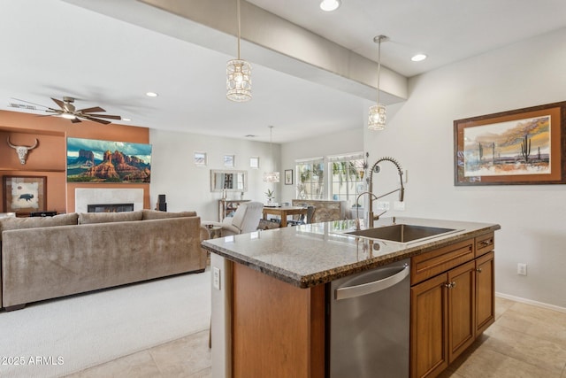 kitchen with stone countertops, a lit fireplace, a sink, dishwasher, and decorative light fixtures