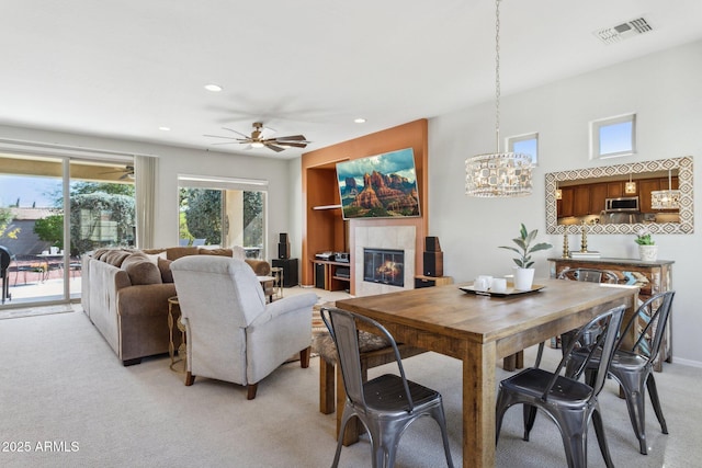 dining space featuring visible vents, a fireplace, recessed lighting, ceiling fan with notable chandelier, and light colored carpet