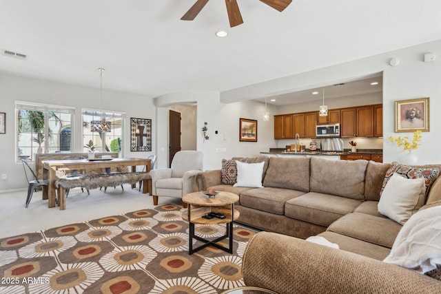 living area featuring recessed lighting, visible vents, light colored carpet, and ceiling fan with notable chandelier