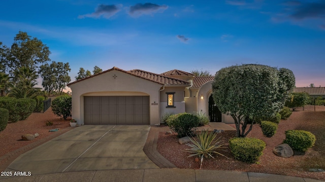 mediterranean / spanish-style house featuring fence, driveway, stucco siding, a garage, and a tiled roof