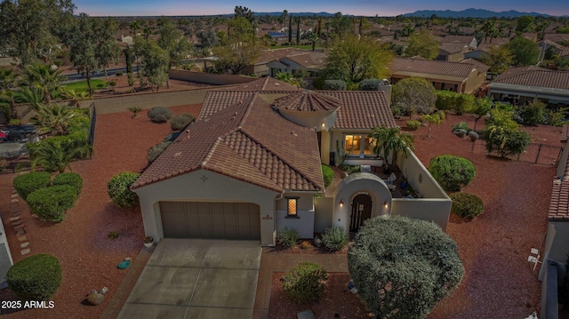 view of front facade featuring an attached garage, stucco siding, concrete driveway, a tile roof, and a mountain view