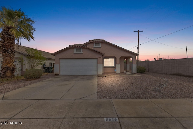 view of front of house featuring a tiled roof, an attached garage, fence, concrete driveway, and stucco siding
