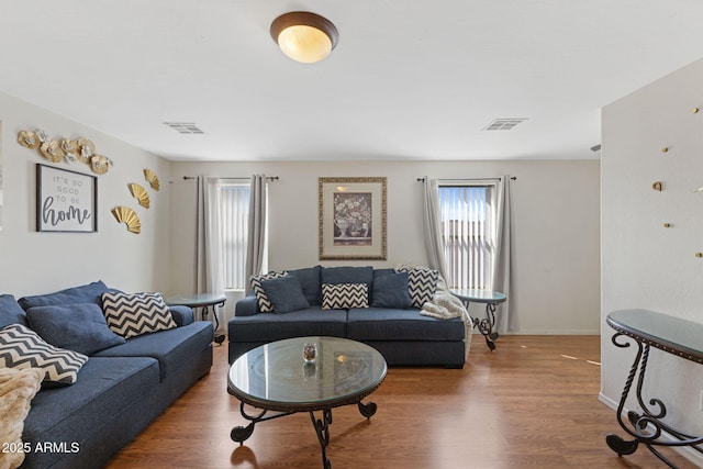 living area featuring visible vents, wood finished floors, and a healthy amount of sunlight
