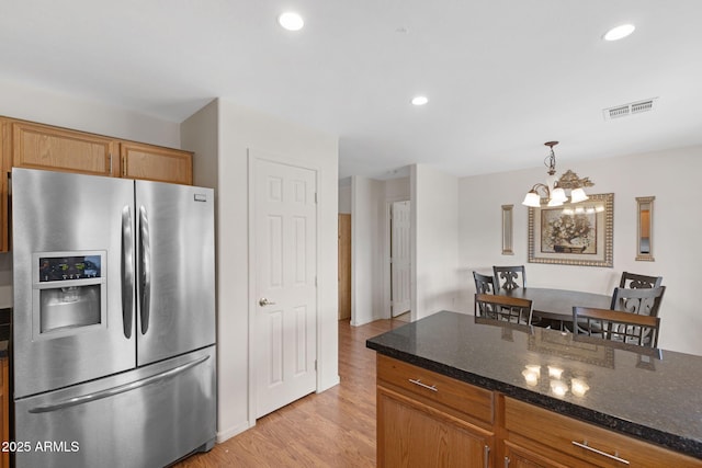 kitchen with stainless steel fridge, a chandelier, decorative light fixtures, visible vents, and light wood finished floors