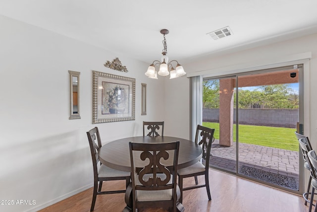 dining room featuring a chandelier, wood finished floors, baseboards, and visible vents