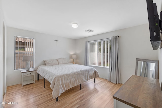 bedroom featuring light wood finished floors, visible vents, multiple windows, and baseboards