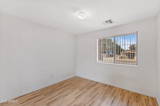unfurnished room with visible vents, baseboards, and wood finished floors