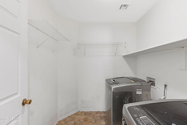 washroom featuring visible vents, baseboards, washer and dryer, and laundry area
