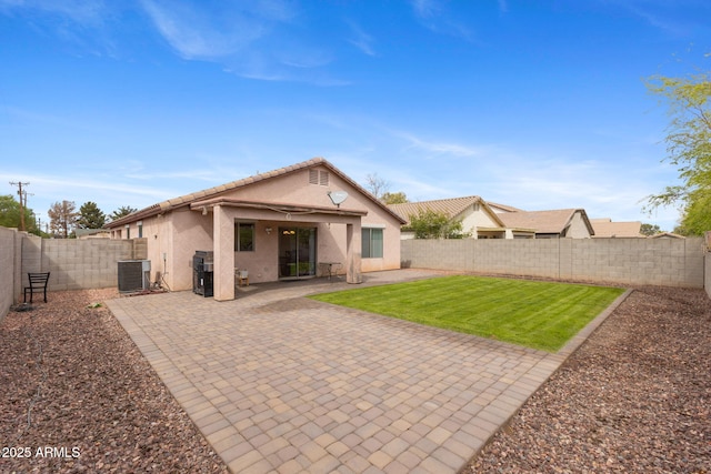 rear view of house with a yard, a fenced backyard, stucco siding, a patio area, and a tile roof