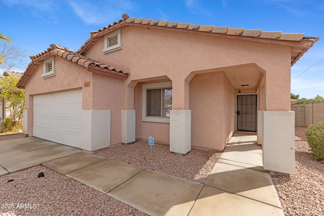 view of front facade with stucco siding, driveway, a garage, a tiled roof, and fence