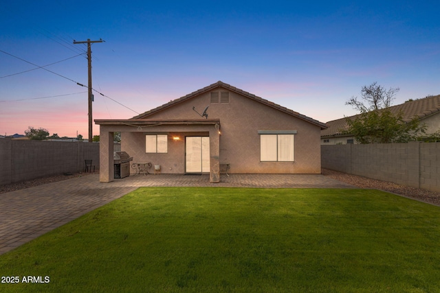 back of house featuring a patio area, a fenced backyard, a yard, and stucco siding
