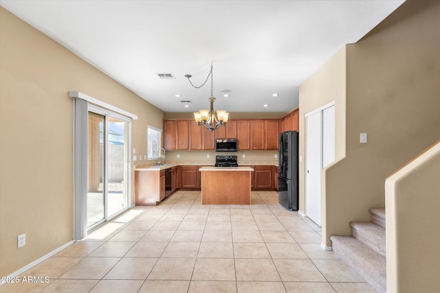 kitchen with a kitchen island, decorative light fixtures, light tile patterned floors, and black appliances