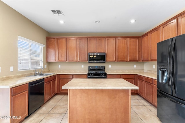 kitchen featuring sink, light tile patterned floors, black appliances, and a center island