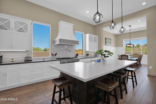 29067 N 71st Ave, Peoria, AZ 85383 - kitchen with custom range hood, wood finished floors, white cabinets, a breakfast bar area, and recessed lighting