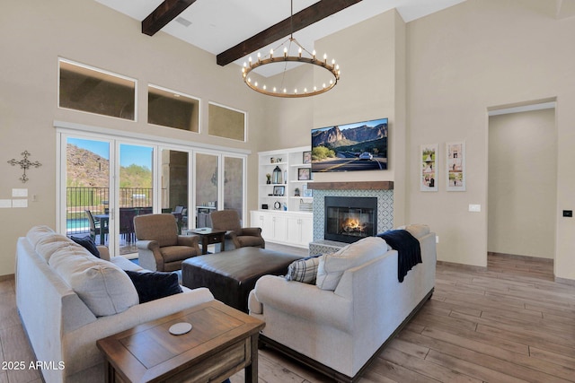 29067 N 71st Ave, Peoria, AZ 85383 - living room featuring a towering ceiling, a chandelier, light wood-style floors, beamed ceiling, and a tiled fireplace