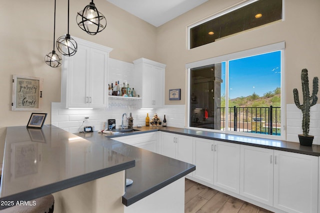 29067 N 71st Ave, Peoria, AZ 85383 - kitchen with a peninsula, dark countertops, white cabinetry, tasteful backsplash, and light wood finished floors