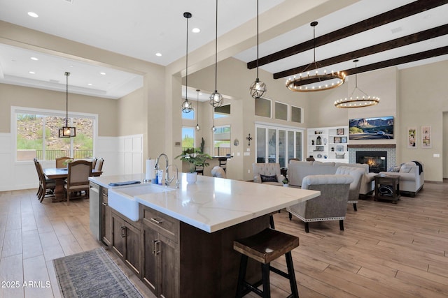 29067 N 71st Ave, Peoria, AZ 85383 - kitchen with light wood-style floors, a glass covered fireplace, dark brown cabinets, light stone counters, and a high ceiling