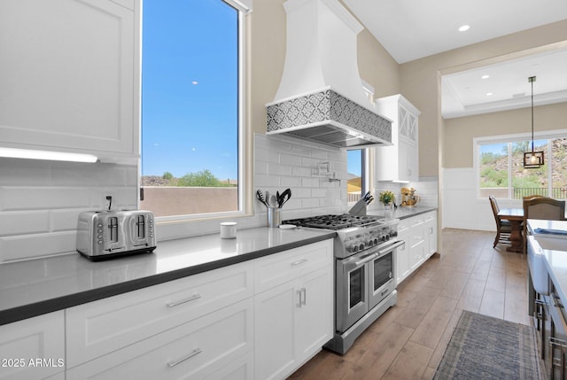 29067 N 71st Ave, Peoria, AZ 85383 - kitchen with range with two ovens, custom range hood, white cabinets, wood finished floors, and tasteful backsplash