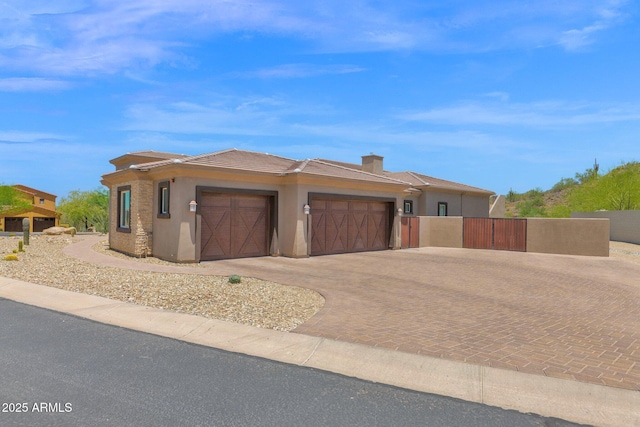 29067 N 71st Ave, Peoria, AZ 85383 - view of front facade featuring an attached garage, a gate, decorative driveway, stucco siding, and a chimney