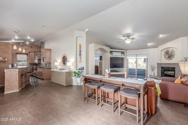 kitchen featuring track lighting, dark hardwood / wood-style flooring, decorative backsplash, ceiling fan, and a tiled fireplace