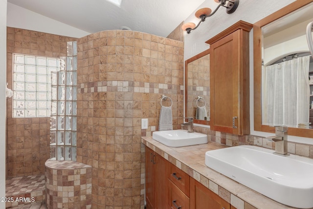 bathroom featuring vanity, vaulted ceiling, and tiled shower