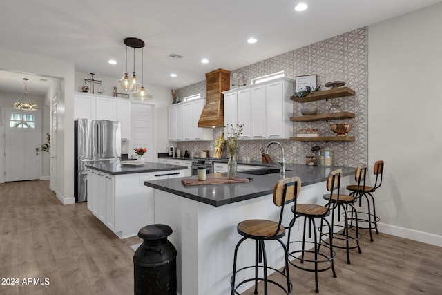 kitchen featuring white cabinets, kitchen peninsula, decorative light fixtures, stainless steel appliances, and custom range hood