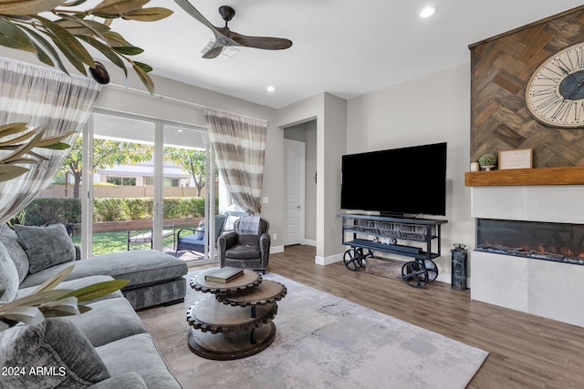 living room featuring ceiling fan, a fireplace, and hardwood / wood-style floors