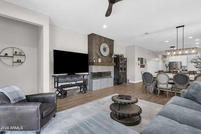 living room featuring wood-type flooring, ceiling fan, and a tiled fireplace