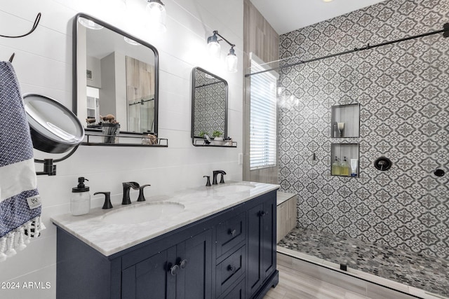 bathroom featuring hardwood / wood-style floors, vanity, tiled shower, and tile walls