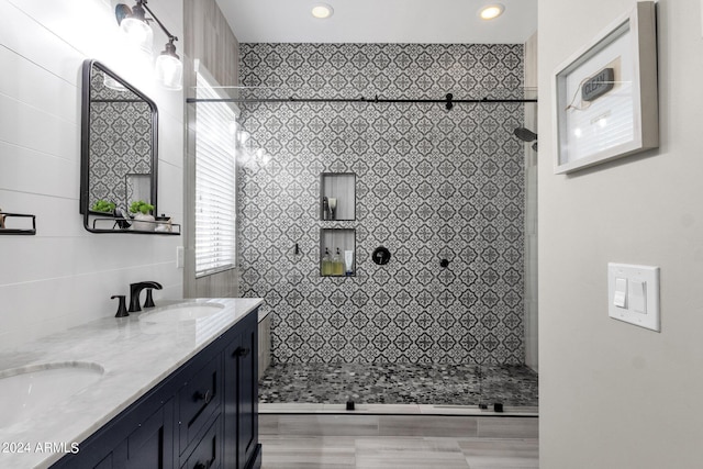 bathroom featuring wood-type flooring, vanity, tile walls, and a tile shower