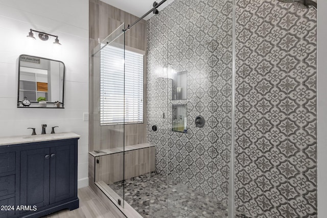 bathroom with a shower with door, vanity, and tile walls