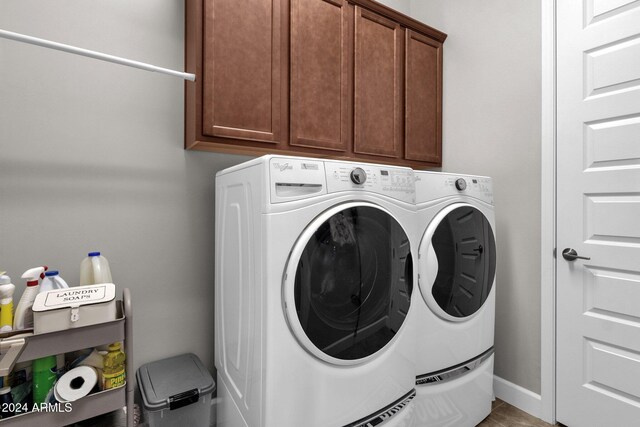 clothes washing area with washing machine and dryer and cabinets