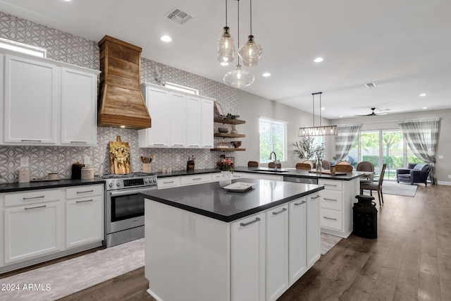 kitchen featuring a center island, dark hardwood / wood-style floors, premium range hood, high end range, and hanging light fixtures