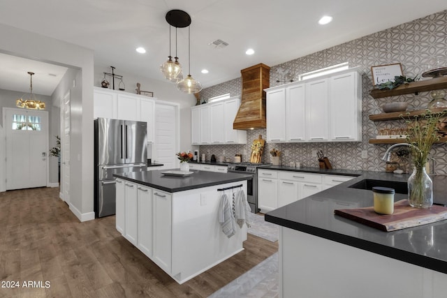 kitchen featuring white cabinets, premium range hood, sink, decorative light fixtures, and appliances with stainless steel finishes