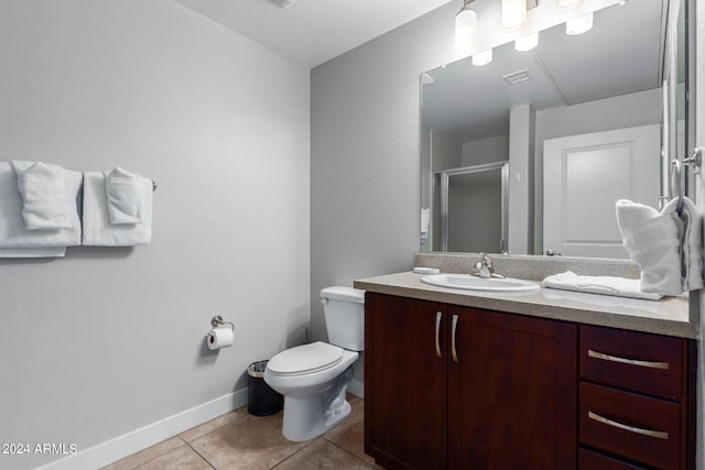 bathroom featuring tile patterned flooring, vanity, a shower with shower door, and toilet