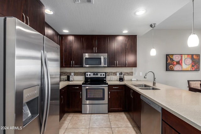 kitchen featuring appliances with stainless steel finishes, hanging light fixtures, kitchen peninsula, sink, and decorative backsplash