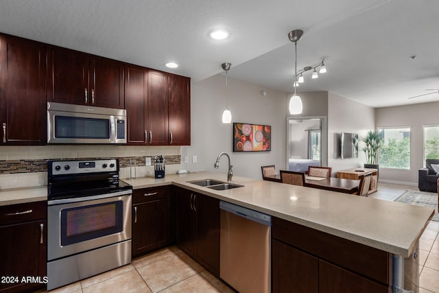 kitchen featuring decorative light fixtures, appliances with stainless steel finishes, kitchen peninsula, sink, and light tile patterned flooring