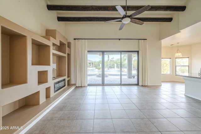 unfurnished living room featuring baseboards, built in features, a towering ceiling, beamed ceiling, and light tile patterned flooring