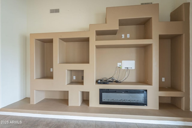 details featuring built in shelves, a glass covered fireplace, and visible vents