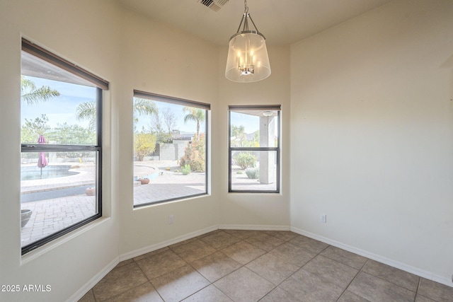 unfurnished room featuring a chandelier, light tile patterned floors, and baseboards