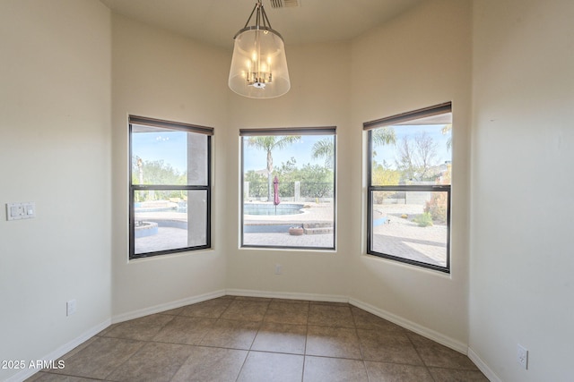 tiled spare room featuring a towering ceiling, an inviting chandelier, visible vents, and baseboards